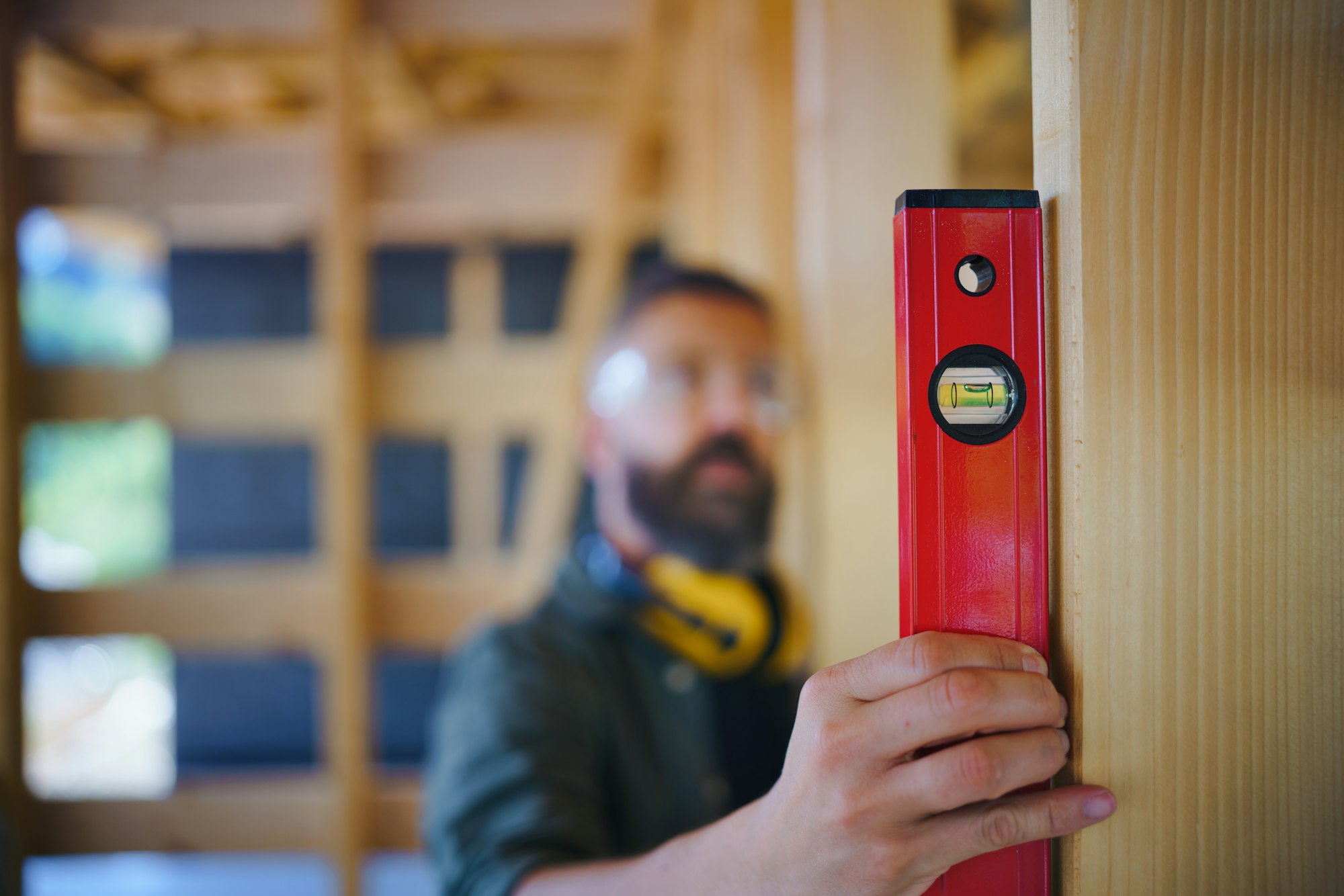 Carpenter checking wooden planks with spirit level, diy eco-friendly homes concept.