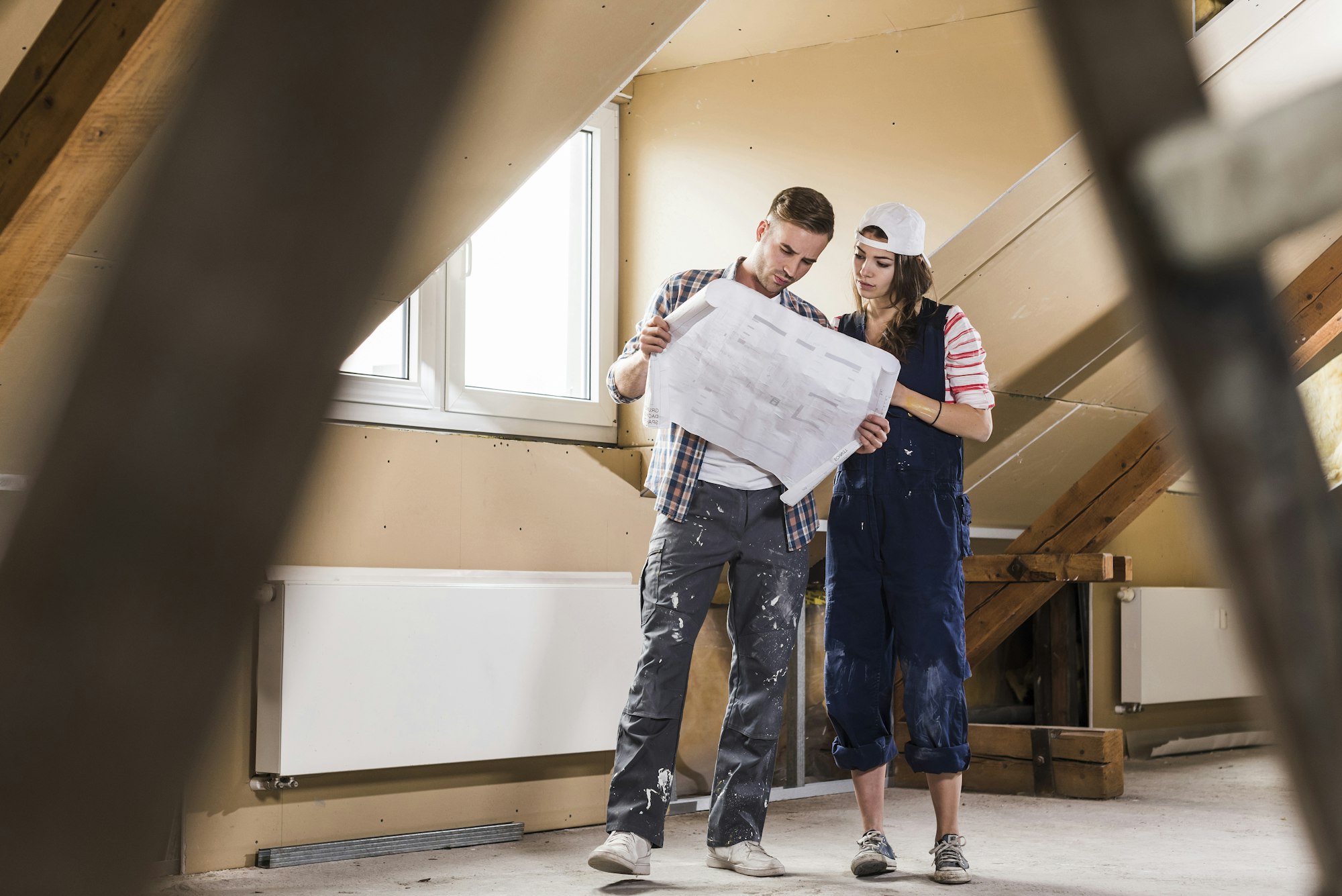 Young couple on construction site of their new home, looking at construction plan